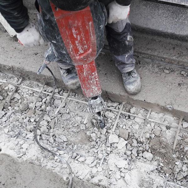 Robotnik kujący beton za pomocą młota udarowego